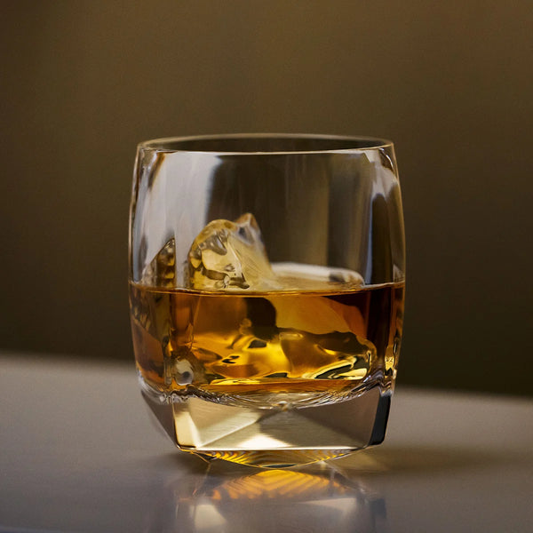 A heavy crystal tumbler filled with whiskey and ice
