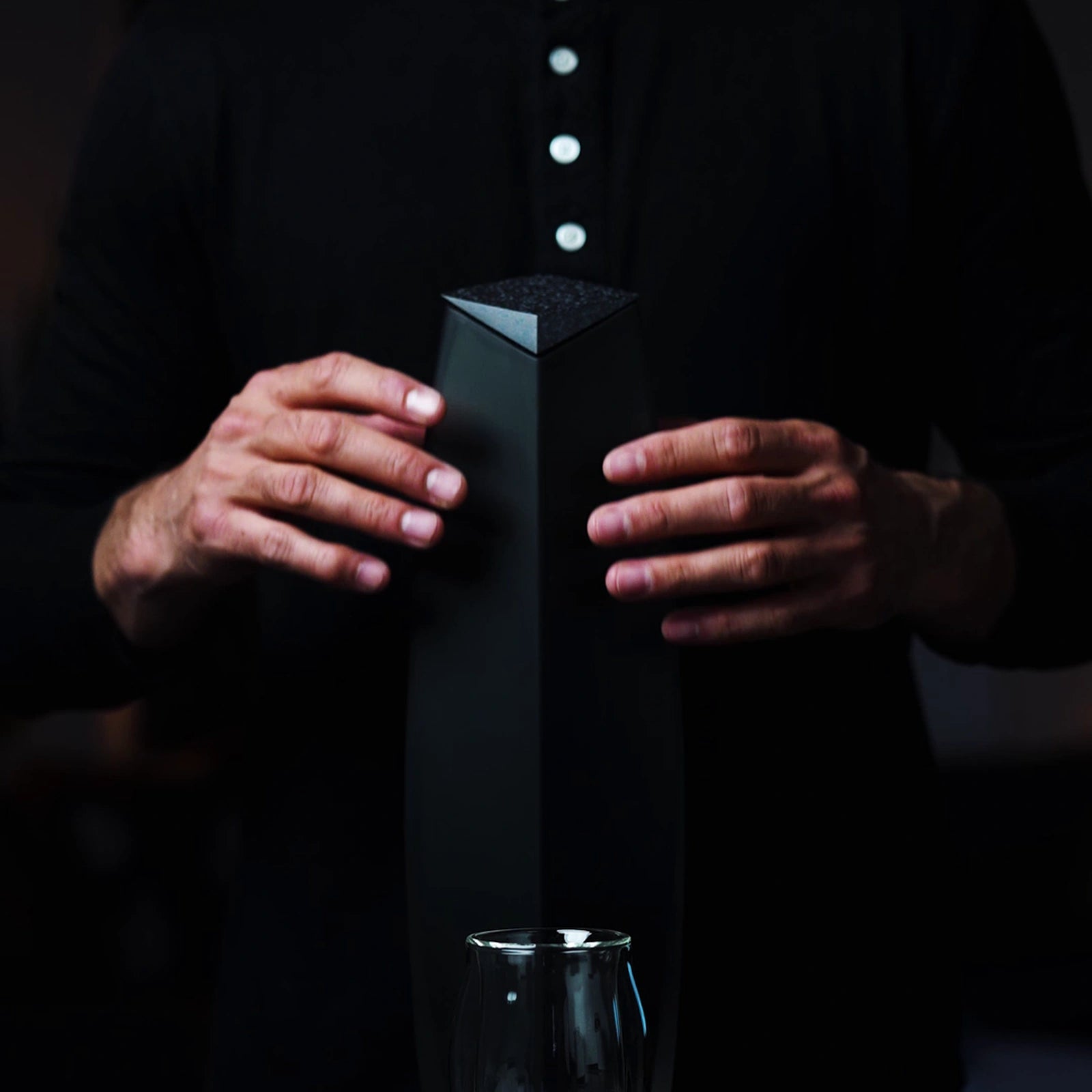 Two hands enclosing around  the  Raif Whisky Decanter by Norlan